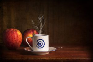 Mug of tea with two apples behind