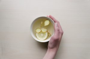 Hand holding tea with lemon slices floating