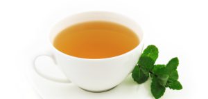 White tea cup with mint leaves beside