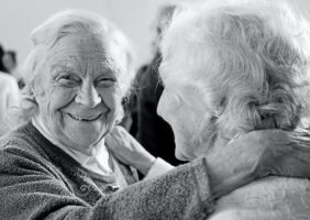 elderly women touching shoulders