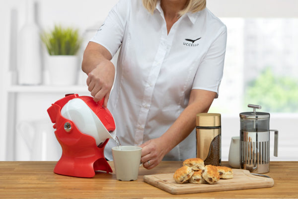 Lady using the tilt-to-pour action of the red and white Uccello Kettle