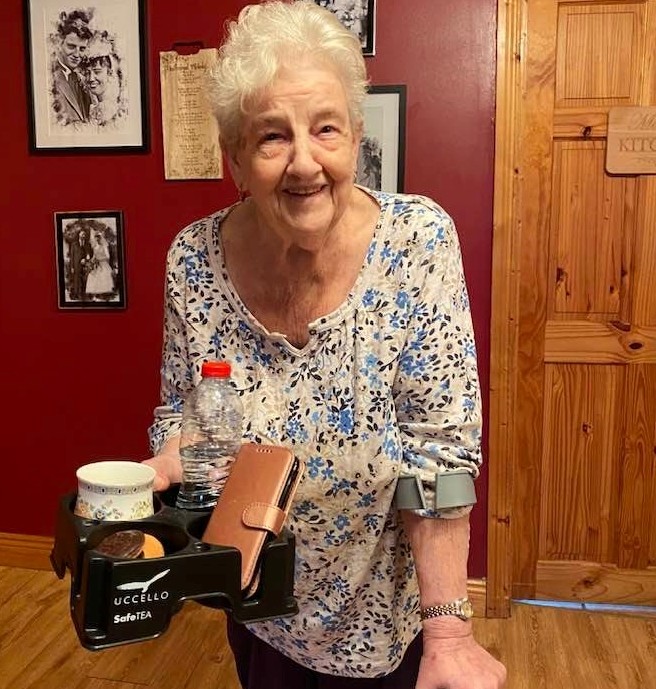 Grandmother on crutch carrying tea, biscuits water bottle and phone with her Muggi Cup Holder