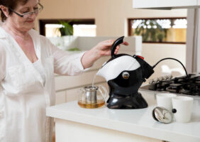 Woman using the tilt to pour action of the Uccello Kettle Tipper