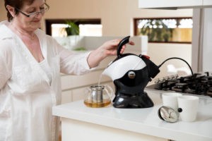 Woman using the tilt to pour action of the Uccello Kettle Tipper