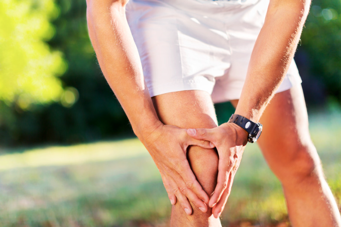 Man outside holding his painful knee