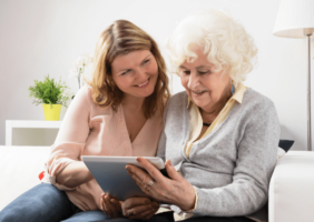 Older daughter teaching senior mother how to use the ipad