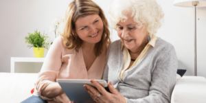 Older daughter teaching senior mother how to use the ipad