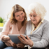 Older daughter teaching senior mother how to use the ipad