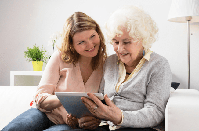 Older daughter teaching senior mother how to use the ipad