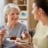 Adult daughter eating cake with her elderly mother